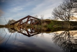 FILE - An old railway bridge blown up by the British Army in the 1970s is partially submerged in the Belcoo River that separates Northern Ireland from the town of Blacklion, Republic of Ireland, Dec. 23, 2019.