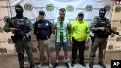 Esta fotografía publicada por la Oficina de Prensa de la Policía Nacional de Colombia muestra a quien identifican como el ciudadano británico Christopher Neil, en el centro, tal como lo muestran a la prensa en Medellín, Colombia, el viernes 13 de diciembre de 2024. 