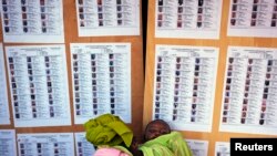 A woman holding a baby searches for her name on a list of eligible voters at an election center in Bamako, July 23, 2013.