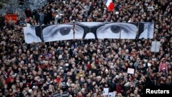 Warga memegang panel untuk menciptakan gambar mata editor Charlie Hebdo, Stephane Charbonnier, saat ratusan ribu warga ambil bagian dalam pawai solidaritas di Paris (11/1). (Reuters/Charles Platiau)