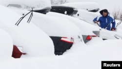 Un homme déneige sa voiture à Saint-Chaffrey, France, le 1er mars 2018.