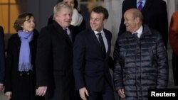 Britain's Foreign Secretary Boris Johnson, center left, and France's President Emmanuel Macron, center right, prepare for a group photo at the Royal Military Academy Sandhurst, during UK-France summit talks in Sandhurst, Britain, Jan. 18, 2018.