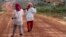 FILE - Women walk past houses, built for the residents being displaced by land sales, at Botum Sakor National Park in Koh Kong province, Feb. 20, 2012. About 200 families displaced by construction have returned to their homes, demanding more compensation.