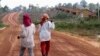 FILE - Women walk past houses, built for the residents being displaced by land sales, at Botum Sakor National Park in Koh Kong province, Feb. 20, 2012.