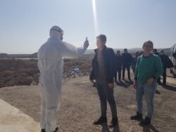At the border between Syria and Iraq, health workers take the temperature of travelers as they arrive in Iraq in response to the coronavirus outbreak. Later that day, the Syria border closed for the same reason, Feb. 27, 2020. (VOA/Heather Murdock)