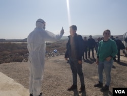 At the border between Syria and Iraq, health workers take the temperature of travelers as they arrive in Iraq in response to the coronavirus outbreak. Later that day, the Syria border closed for the same reason, Feb. 27, 2020. (VOA/Heather Murdock)