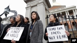 FILE - Massachusetts residents Jessica Wong, front left, Jenny Chiang, center, and Sheila Vo, protest racism against Asians during the coronavirus pandemic that originated in China, in Boston, Massachusetts, March 12, 2020.