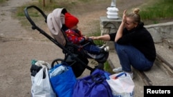 为逃离俄军的轰炸，一名哭泣的乌克兰妈妈和她的一岁的儿子正在等候大巴车疏散到哈尔科夫。（2024年5月14日）