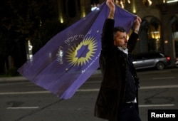 A supporter of the Georgian Dream party carries the party's flag in the street after the announcement of exit poll results in parliamentary elections, in Tbilisi, Georgia, on Oct. 26, 2024.