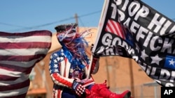 Micki Larson-Olson sostiene una bandera cerca del sitio donde el gobernador de Texas, Greg Abbott, y sus compañeros gobernadores se reunirán a lo largo del Río Grande, en la frontera entre Estados Unidos y México, el domingo 4 de febrero de 2024, en Eagle. Pase, Texas.