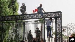 FILE: Tunisian soldiers guard the main entrance of the parliament as demonstrators gather outside the the gate in Tunis, Tunisia. Taken Mon. July 26, 2021. 