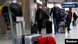 Para penumpang mengenakan masker di bandara Charles de Gaulle dekat Paris, Perancis yang lebih sepi akibat perebakan virus korona. 