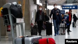 People wearing protective face masks arrive at Charles de Gaulle airport near Paris, France, as the coronavirus outbreak continues to expand, Feb. 29, 2020.