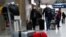 People wearing protective face masks arrive at Charles de Gaulle airport near Paris, France, as the coronavirus outbreak continues to expand, Feb. 29, 2020.
