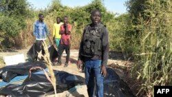 FILE - TOPSHOT - A man stands next to body bags of farmers that were victims of an attack, in the Zabarmari district, near Maiduguri, on November 6, 2023.