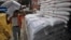 A laborer unloads sacks filled with rice at a wholesale grain market in the northern Indian city of Chandigarh, July 29, 2014.