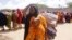 A woman, who fled amid a drought, carries her baby at a makeshift camp for displaced people on the outskirts of Mogadishu, Somalia on Tuesday, Sept. 26, 2023.
