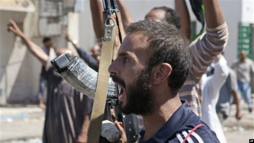In this Sunday, Aug. 14, 2011 photo, a Libyan rebel fighter in Zawiya, western Libya, reacts to the news that the city of Surman, an important strategic point, is now under the control of the rebel forces.