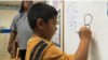 Oklahoma Cherokee language immersion school student writing in the Cherokee syllabary.