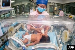 FILE - This file photo taken on May 12, 2023 shows a nurse taking care of a newborn baby at a hospital in Taizhou. China's population shrank in 2023 as the country's birth rate slows in the face of mounting financial pressures and shifting social attitudes. (Photo by AFP)