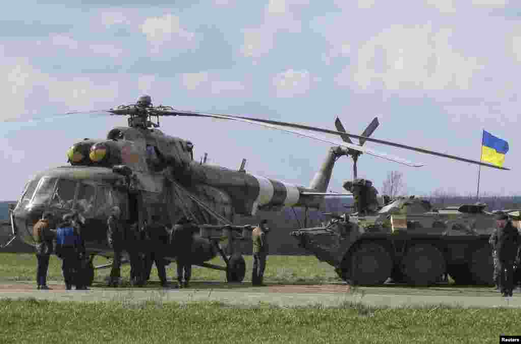 Ukrainian soldiers are seen near a MI-8 military helicopter and armored personnel carrier at a checkpoint near the town of Izium in Eastern Ukraine, April 15, 2014. 