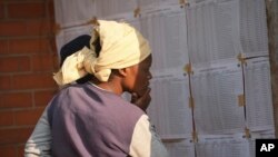 FILE - A woman looks for her name, outside a polling station in Harare, Thursday, Aug. 24 2023.