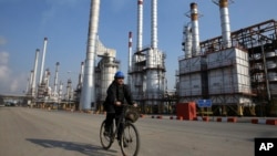 FILE - Iranian oil worker rides his bicycle at the Tehran's oil refinery south of the capital Tehran, Iran.