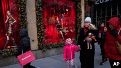 FILE - People walk by holiday windows at Saks Fifth Avenue in New York,Dec. 5, 2018.