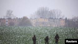 Polish soldiers walk in the field near the site of a purported missile striek in Przewodow, a village in eastern Poland near the border with Ukraine, on November 17, 2022. (Kacper Pempel/Reuters)