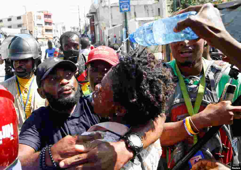 Journalists help a colleague who fainted after police fired tear gas during a protest against Haiti&#39;s President Jovenel Moise, in Port-au-Prince, Feb. 10, 2021.