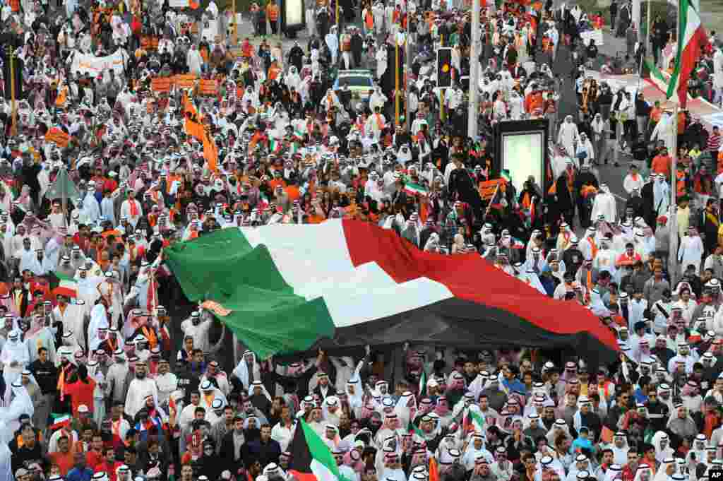 Islamist, nationalist and liberal opposition groups carry a large national flag as they protest the Kuwait government's amendment of the electoral law and support a boycott on the country's election - Friday, Nov. 30