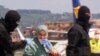 In this image taken from a video, Silvia Romano is flanked by two masked security officers as she walks on the tarmac after landing at Rome's Ciampino airport, May 10, 2020. 