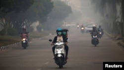 Para pengendara sepeda motor mengenakan masker saat melintasi jalanan di Palangkara Raya, Kalimantan tengah, yang diselimuti oleh kabut asap akibat kebakaran hutan, 15 September 2019. (Foto: dok).