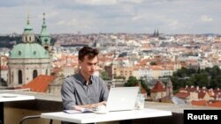 Joseph Petrila, un joven de 23 años que busca empleo, usa una computadora en un café cerca del Castillo de Praga durante la pandemia del coronavirus en julio del 2020.
