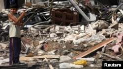 A boy stands near rubble and damaged buildings after what activists said was shelling by forces loyal to Syria's President Bashar al-Assad, in Raqqa province, east Syria, May 2, 2013.