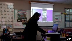 Wylona Rogers teaches students attending a class in-person as well as students attending virtually at Driggers Elementary School, Monday, Feb. 8, 2021, in San Antonio. (AP Photo/Eric Gay)