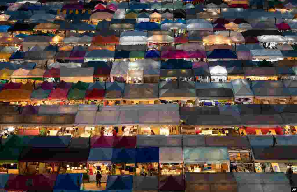 Tents of food stalls and other vendors are illuminated at Rot Fai Market in Bangkok, Thailand.