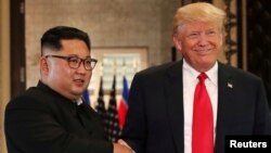 Presiden AS Donald Trump (kanan) dan pemimpin Korea Utara Kim Jong Un dalam pertemuan pertama di Singapura, 12 Juni lalu. 