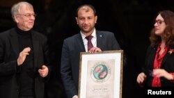Raed al-Saleh (C), head of the Syria Civil Defense 'White Helmets', receives the Right Livelihood Award prize from Jakob von Uexkull (L), the founder of the award, during a ceremony at the Vasa Museum in Stockholm, Sweden, Nov. 25, 2016.