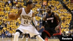 Paul George (24), avant d’Indiana Pacers, entame un drible au milieu de la défense de Miami avec Heat LeBron James (6) en tête, au cours du quatrième quart du cinquième match de la finale des Playoffs de la Conférence Est de la NBA 2014, au Bankers Life 