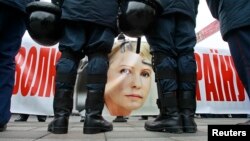 A banner with the portrait of jailed former prime minister Yulia Tymoshenko is seen as police stand guard during an opposition rally in front of the Parliament building in Kyiv, Nov. 13, 2013.