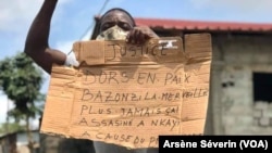 Un homme tient un panneau pour demander justice, à Nkayi au Congo-Brazzaville, le 30 septembre 2020. (VOA/Arsène Séverin)