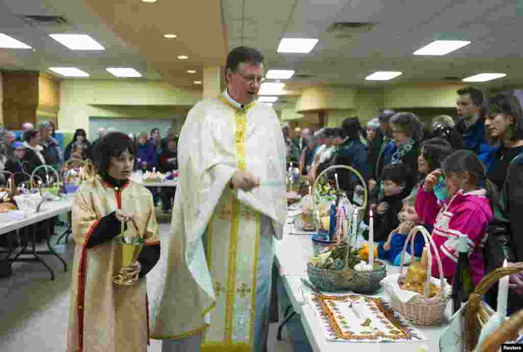 Father Dmytro Dnistrian blesses Ukrainian Easter baskets filled with traditional food for Sunday's Easter dinner at Saints Peter and Paul Ukrainian Catholic Church in Saskatoon, Alberta, April 19, 2014. REUTERS/Todd Korol (CANADA - Tags: RELIGION) - RTR3