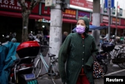 A woman wearing a protective face mask is seen at a residential community following an outbreak of coronavirus (COVID-19), in downtown Shanghai, China, March 13, 2020.