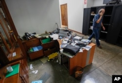 In this Dec. 14, 2018 file photo, Confidencial director Carlos Fernando Chamorro, son of former President Violeta Barrios de Chamorro, walks through his ransacked offices while talking on his cell phone in Managua, Nicaragua.