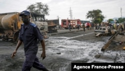 A man walks past burnt vehicles in Freetown on Nov. 6, 2021, following a massive explosion that has killed at least 91 people.