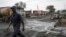 A man walks past burnt vehicles in Freetown on Nov. 6, 2021, following a massive explosion that has killed at least 91 people.