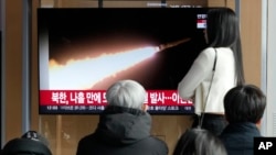 28일 한국 서울 시내 철도역 이용객들이 북한 순항미사일 발사 관련 TV 뉴스를 시청하고 있다. 