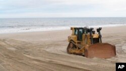 Una topadora en la playa Mantoloking, Nueva Jersey, lleva a cabo la reposición de arena en una área azotada por la supertormenta Sandy en 2012.