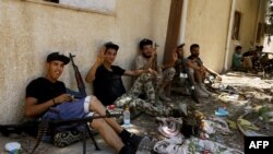 Fighters loyal to the internationally-recognized Libyan Government of National Accord (GNA) take a rest near their weapons in the al-Sawani area during clashes with forces loyal to Libya strongman Khalifa Haftar, June 19, 2019.